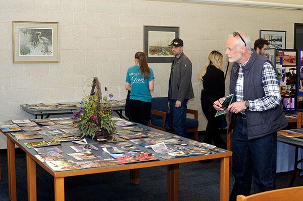 Alumni move among ESC library tables, on which historic images were arrayed. Guests were encouraged to write any identifying information on the photos for preservation in the college archives. 
