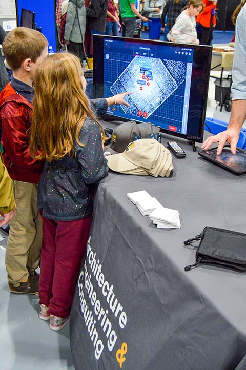 Children look at a 3D model rendering of the Field House on a Larson Design Group monitor.