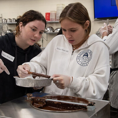 In the baking and pastry arts lab, students from Jersey Shore Area Senior High School dip pretzels into tempered chocolate.