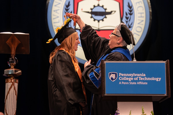 The president moves Flanagan's tassel from right to left, signifying her official ascension to a higher level of learning.