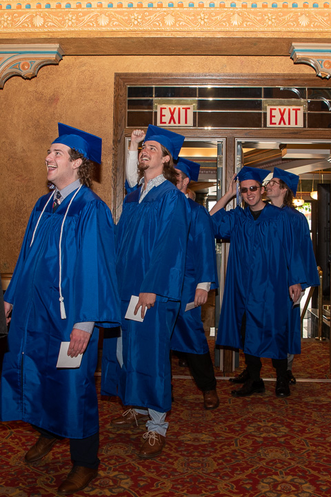 Delighted by their faculty members’ shouts from the inner lobby balcony and stairs, these grads make a grand entrance (before their final exit).