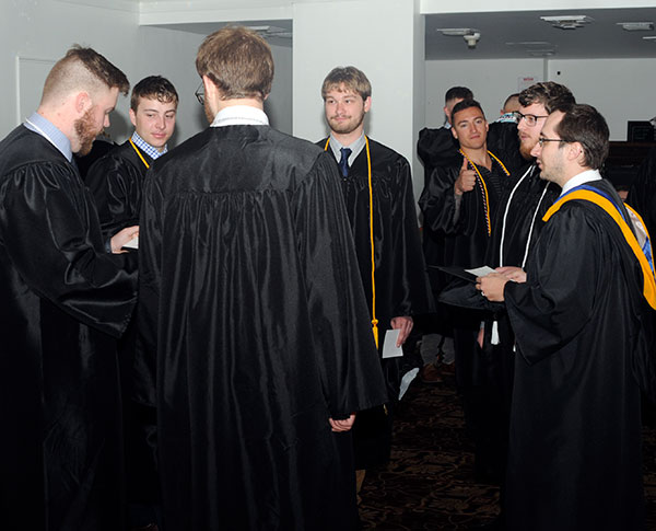 Plastics technology instructor Joshua J. Rice (right), honored with an Excellence in Teaching Award on Thursday, talks with soon-to-be-grads prior to the Saturday morning procession. Giving the photographer a 