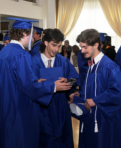 Celebratory students assess the quality of a cellphone memento.
