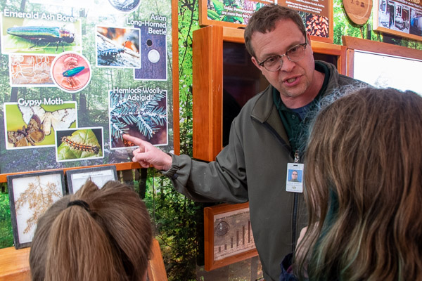 Darrel Showers, of the Pennsylvania Department of Agriculture, engages girls in a conversation about invasive bugs that damage Pennsylvania trees (including the spotted lanternfly, emerald ash borer, spongy moth and hemlock woolly adelgid).