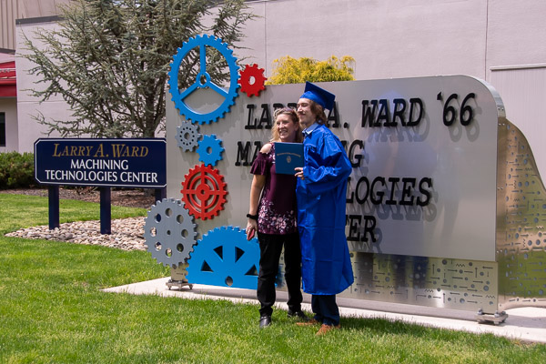 Noah M. Cooper, a welding technology student grad from Shavertown, poses with family in front of one of the coolest building signs on campus.