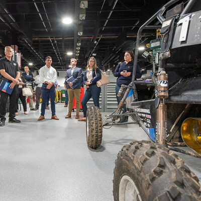 Michael J. Reed (left), who will assume the presidency on Friday, talks with the group in the Larry A. Ward Machining Technologies Center. In the foreground is Penn College's Baja SAE car, recently driven by students to back-to-back endurance titles against formidable challengers in national competition.