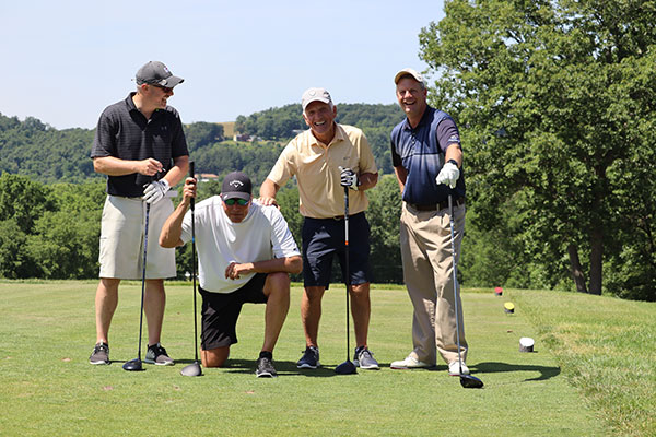 Adding to this foursome's fun, Golf Classic committee member Mark Sitler kneels to lessen his height advantage over teammate Ray Wheeland. Both are members of the Penn College Foundation Board of Directors. 