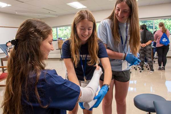 Physician assistant student Kathryn A. Plankenhorn, of Montoursville, serves as the patient while teaching Health Careers participants to apply a cast.<br />
