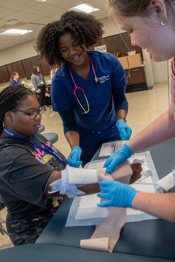 Kori-Ann A. Taylor (center), a physician assistant student from Williamsport, walks a duo through the steps of making a splint.