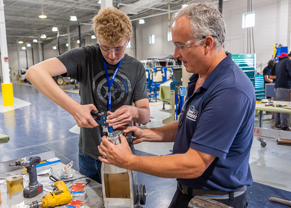 Collision repair instructor Roy H. Klinger (right) helps a camper replicate the detail-oriented world of automotive restoration.