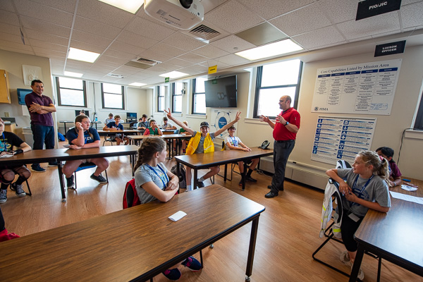 A yellow-vested participant demonstrates his enthusiasm in a group led by David E. Bjorkman (left), emergency management/social science instructor, and William A. Schlosser, project worker (and an incoming instructor in the major). 