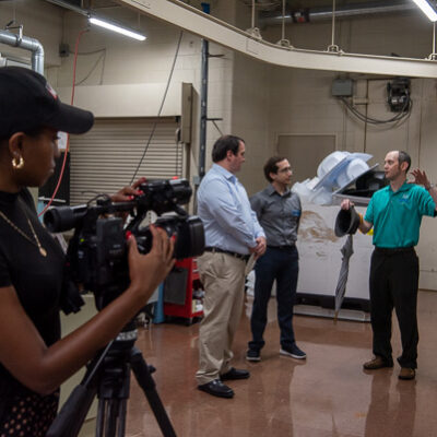 Allen captures footage as (from left) Secretary Weaver, Rice and Webb talk about the career opportunities represented by Penn College's various manufacturing majors.