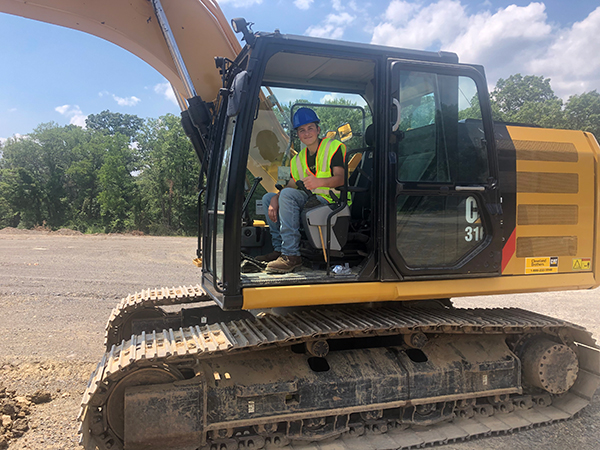 A camper signals his thumbs-up after successfully piloting a Caterpillar excavator.