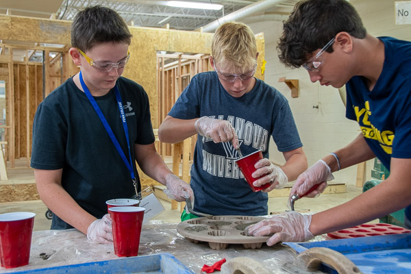 Boys add quick-drying concrete to small molds for a take-home souvenir.