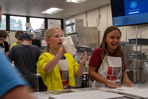 Campers get hands-on experience stretching the dough for their personal pizzas.