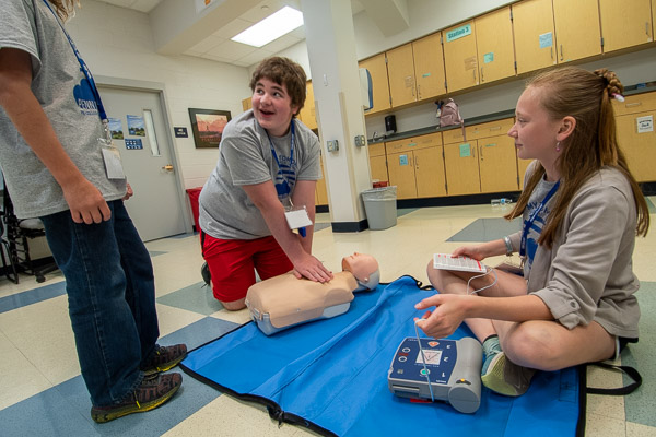 Participants provide chest compressions and apply an automated external defibrillator.