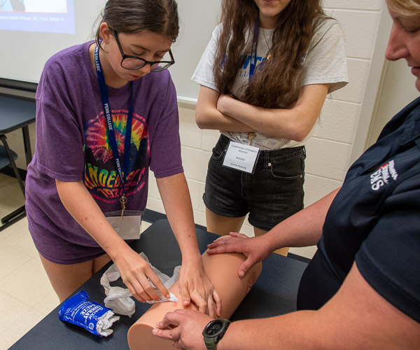 Katie Kieser, a 2018 grad of the college’s paramedic program now employed as a paramedic by Susquehanna Regional Emergency Medical Services, guides participants through packing a wound with combat gauze – a technique used when a cut is not on a limb and won’t benefit from a tourniquet.