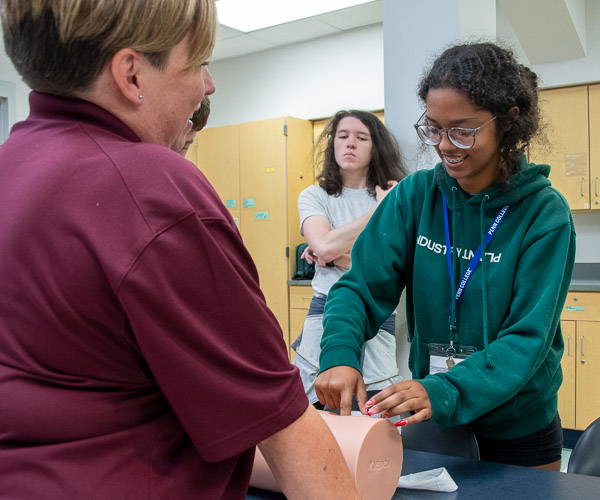 With encouragement from Kathy Kling, ’15, who, along with Kieser, is a Susquehanna Regional EMS paramedic, a participant packs gauze into a manikin’s “gunshot wound.” Both Kling and Kieser are also part-time noncredit instructors at Penn College.
