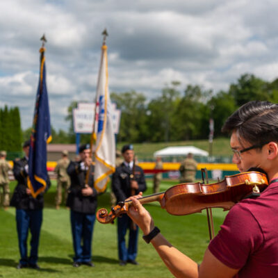 Members present the colors in rehearsal, as violinist Michael Fisher – a Williamsport Area High School graduate studying at the New England Conservatory of Music – performs the national anthem.