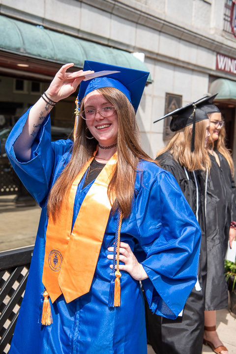 Serenity Hamlin, human services & restorative justice, uses her graduation card to block the intensity of the sunshine as grads wait in line outside the Genetti Hotel. 