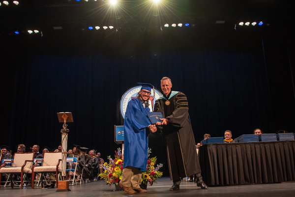 John William Brown, decked out in a blue bow tie to match his gown, pauses to savor center stage. The Littlestown resident earned as associate degree in electric power generation technology: diesel emphasis.