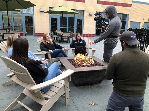Crew members join a group around the Bush Campus Center fire pit, including Caila N. Flanagan, an involved campus leader who transitioned to Residence Life employee after graduating in May with two business degrees. Seated from left are Wildcats Sophia G. Wiest, Lauryn A. Stauffer, Flanagan and Serena V. Bergeron.