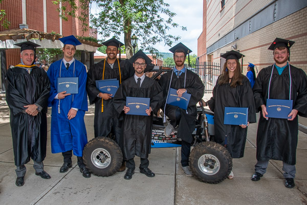 Graduating members of the college’s 2022 Baja SAE team, which made college history by being the first in the team’s 17 years to take first in an endurance race (and then repeated the feat a few weeks later), pose with their winning vehicle – manufactured by them – and their adviser, John G. Upcraft, instructor of machine tool technology/automated manufacturing. The grads missed their spring commencement because they were  competing.