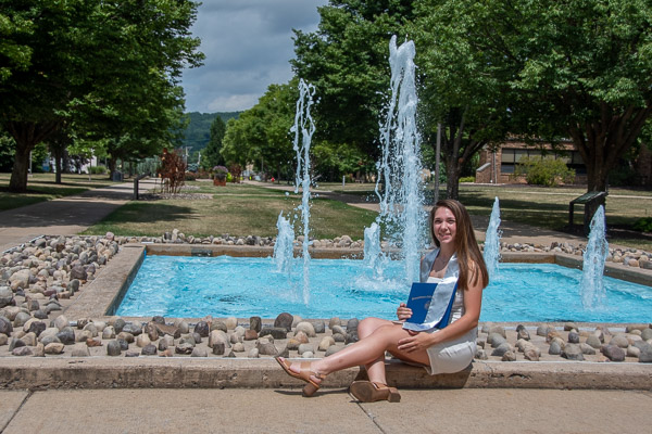 Surgical technology grad Olivia M. Eisenhauer, of New Columbia, celebrates near the Veterans Fountain. Her student-athlete stole was earned through participation on the Wildcat softball team.