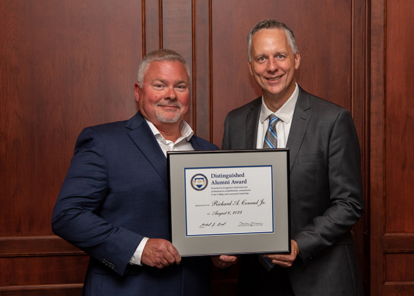Pennsylvania College of Technology Distinguished Alumni Award recipient Richard A. Conrad Jr., of Selinsgrove, (left) receives congratulations from President Michael J. Reed. 