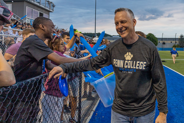 Reed interacts with the overflow crowd, lined up along the fence between the bleachers and the field. In his convocation remarks, he shared three suggestions from graduates: 
