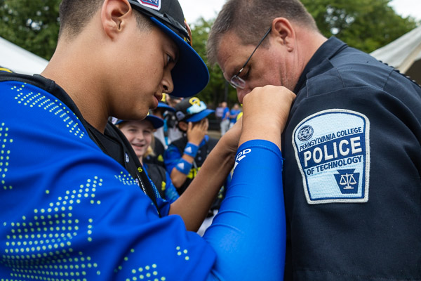 An Australian ballplayer adds a pin to the uniform of Penn College Police Officer Jeffrey E. Kriner.