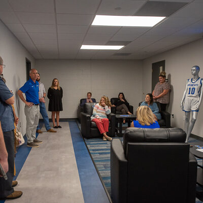 Kennell (left, in blue shirt) welcomes the group to the Klingerman Family Athletics Suite – complete with a participant's photo on the big screen just like recruits see when they arrive. Employees were also introduced to “David” and “Jane,” the manikins modeling Wildcat attire (and whose names honor former college President Davie Jane Gilmour).