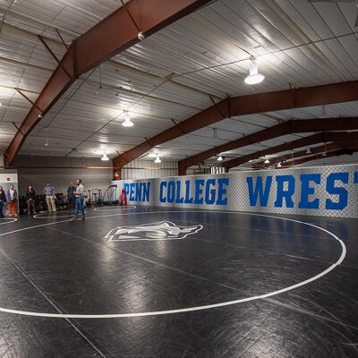 Wrestling coach Pankil Chander (tan pants) and Blymier (center) discuss features of the second-floor loft in the Field House, which the Klingerman Family Wrestling Fund helped renovate and equip.
