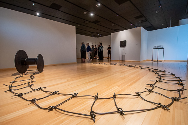 “Bound,” a work of hand-forged steel and ebonized walnut, fronts a group of gallery-goers.
