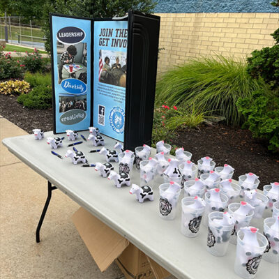 An info table encourages WEB signups and dispenses cow-themed swag.