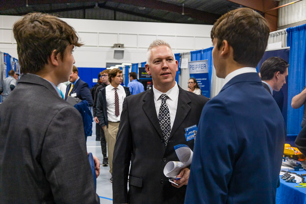 Jason E. Krick, assistant professor of construction management and a double Penn College alumnus ('97, building construction technology; and '98, construction management), encourages equally well-dressed students in the Field House.