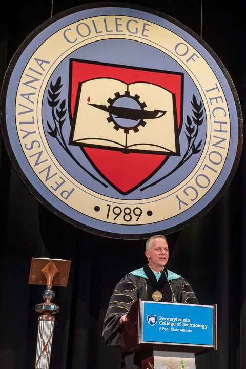 Symbolically standing amid other aspects of tradition and continuity, Penn College's seal and mace, Reed takes his rightful place at the helm.