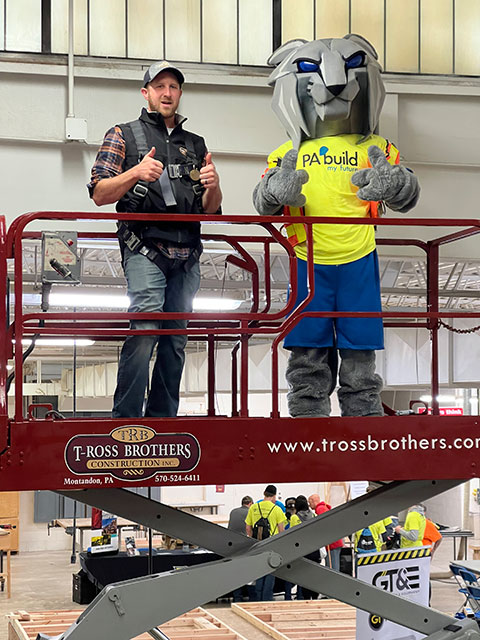 ... and rides a scissor lift with a T-Ross Brothers Construction Inc. rep.