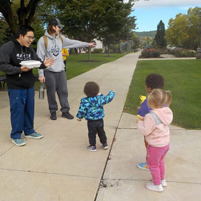 While out and about, on a mission to colorfully add their artistic touch to campus sidewalks, several Bunnies (the center's 2- and 3-year-olds) engage Penn College students in a friendly "chalk talk."