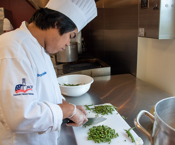 Aguilar uses his knife skills to add green beans to the recipe.