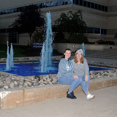 The fountain outside the Breuder Advanced Technology & Health Sciences Center adopts an appropriate tint for the coming weekend, thanks to Wiest (left) and Telesky. Wiest is a landscape/plant production technology student from Butler; Telesky, of Milton, is pursuing a degree in a human services & restorative justice.