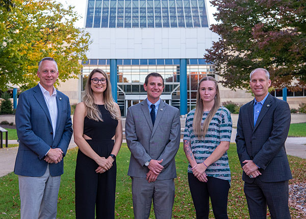 Bookended by President Michael J. Reed (left) and Scott E. Kennell, director of athletics, this year's Hall of Fame inductees stand for a pre-reception photo on the campus mall. From left are Jordan A. (Courter) Rutledge, soccer; Mark C. Shaffer, baseball; and Alicia N. Ross, basketball.
