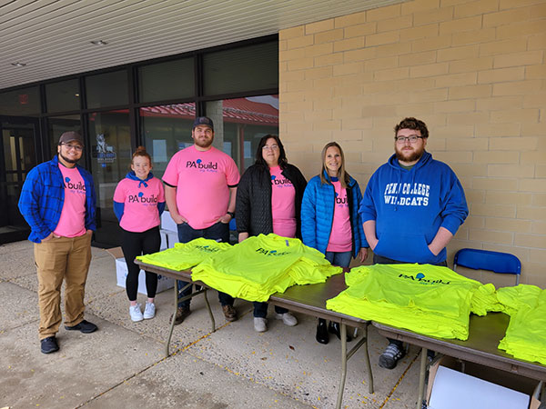 Co-workers from The College Store and students enrolled in emergency management & homeland security staff the T-shirt table, pleasantly sending guests to their next station.