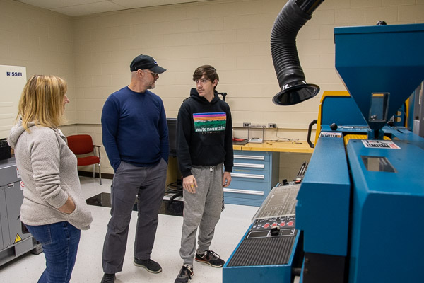 First-year plastics & polymer engineering technology student Joshua R. Kimbel, of Herndon, Va., explains the workings of a hydraulic extruder to his parents, Susanne and Brian.