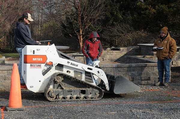 Justin M. Rinehimer (right), owner and operator of Stubb's Landscaping in Mountain Top, keeps a watchful eye on a student skid-steer operator. Rinehimer earned three diplomas from Penn College – associate degrees in landscape/horticulture technology: landscape emphasis and landscape/horticulture technology: plant production emphasis (2017) and a bachelor's in applied management (2018) – and was a member of the Wildcat archery team.