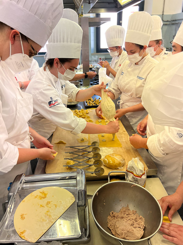 During one of several hands-on cooking classes, students fill tortellini.