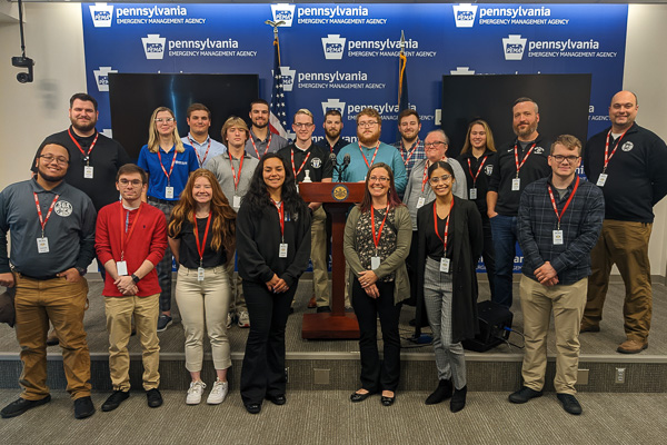 The 20-member Penn College contingent, properly identified with visitor badges, pauses for a group photo during its tour of the Pennsylvania Emergency Management Agency in Harrisburg. Joining students on their inspiring outing is William A. Schlosser (right), emergency management and homeland security instructor.