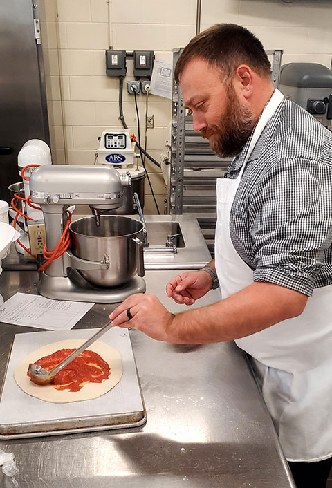 Timothy O. Rissel, executive director of general services, ladles just the right amount of sauce.