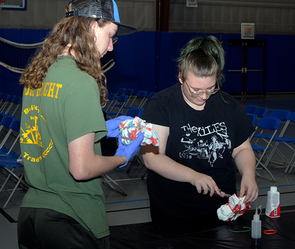 Adding their personal touch to Wildcat Events Board T-shirts at the tie-dying table are first-year students Ralph R. Courtright III, of Milford, construction management, and Kim J. Benny, of Delta, architecture & sustainable design.