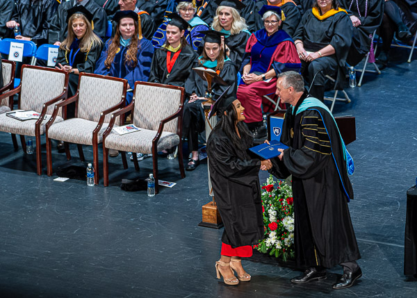 This semester's winner of the President's Award, as well as completing her coursework in human services & restorative justice, Ashlee C. Felix-Taveras shakes hands with Reed.